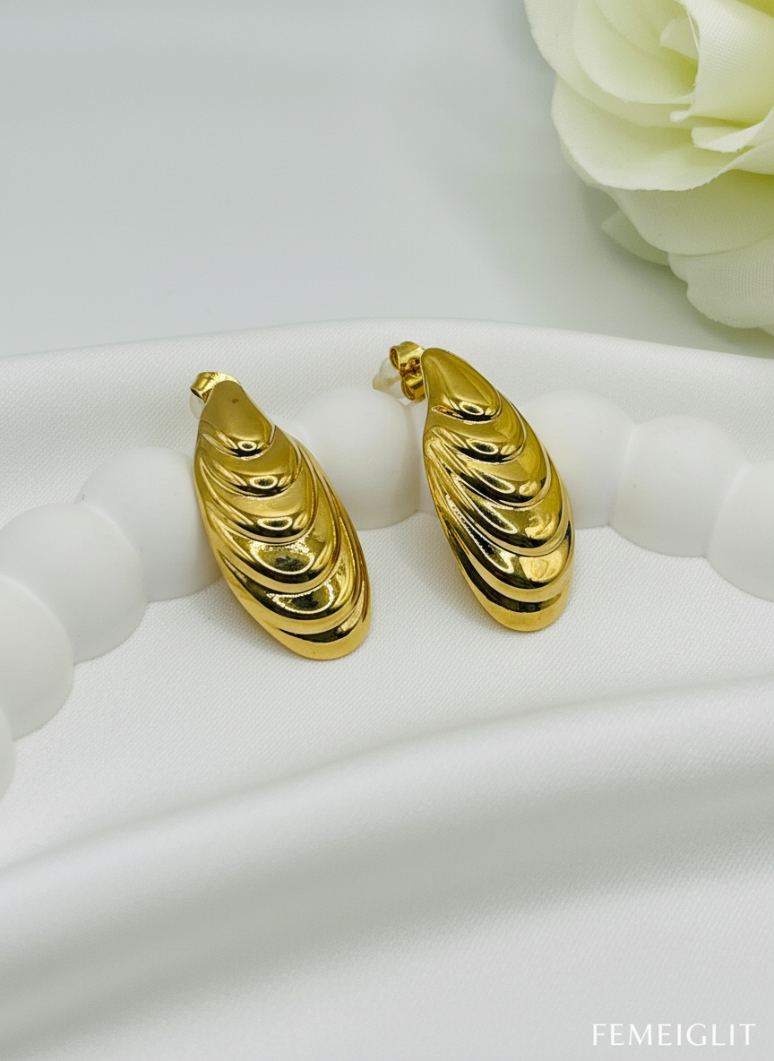 Gold hoop earrings on a white surface with a floral background