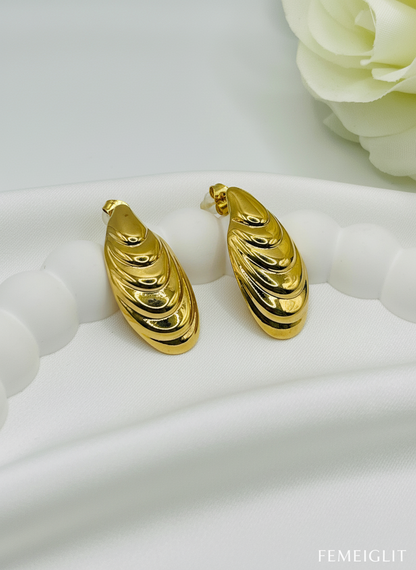 Gold hoop earrings on a white surface with a floral background