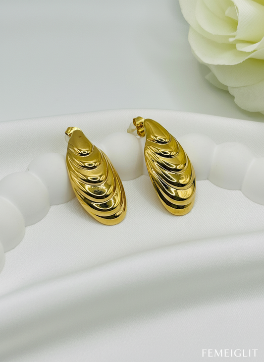 Gold hoop earrings on a white surface with a floral background