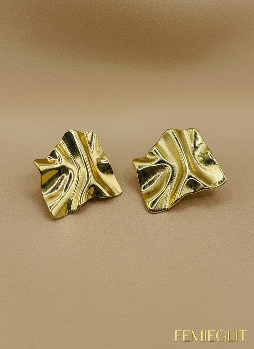 Gold leaf-shaped earrings on a white beaded background