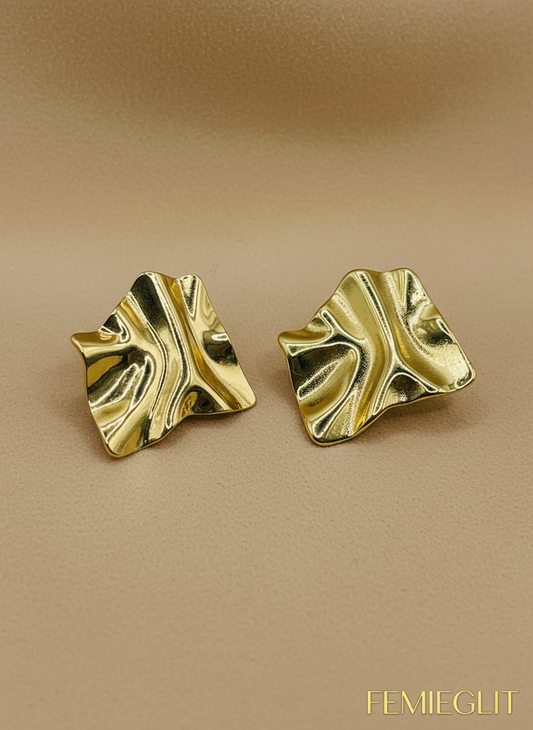 Gold leaf-shaped earrings on a white beaded background