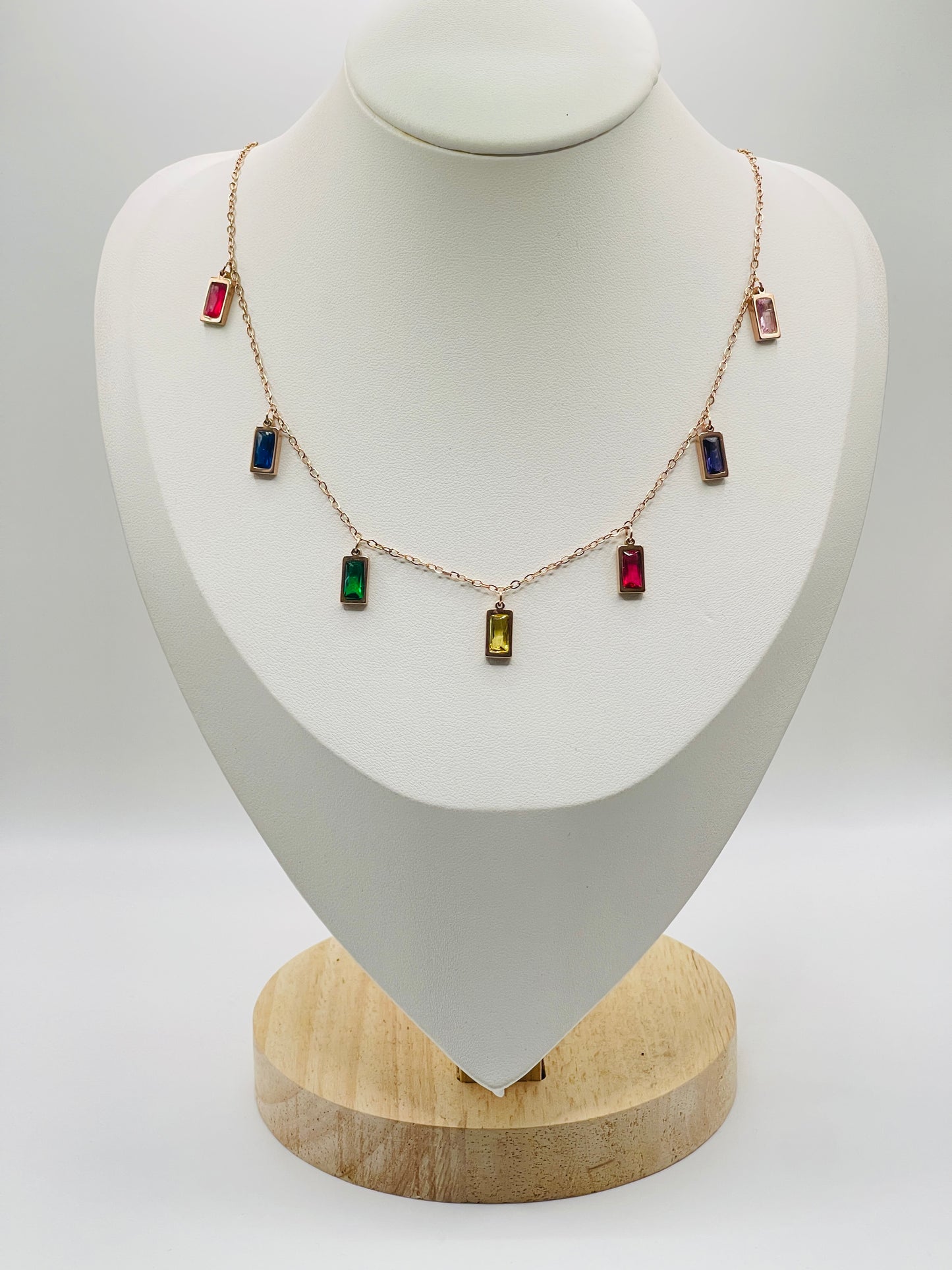 Rose goldNecklace with colorful gemstones on a mannequin bust against a white background