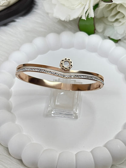 Rose gold bracelet with diamond accents on a white dish with flowers