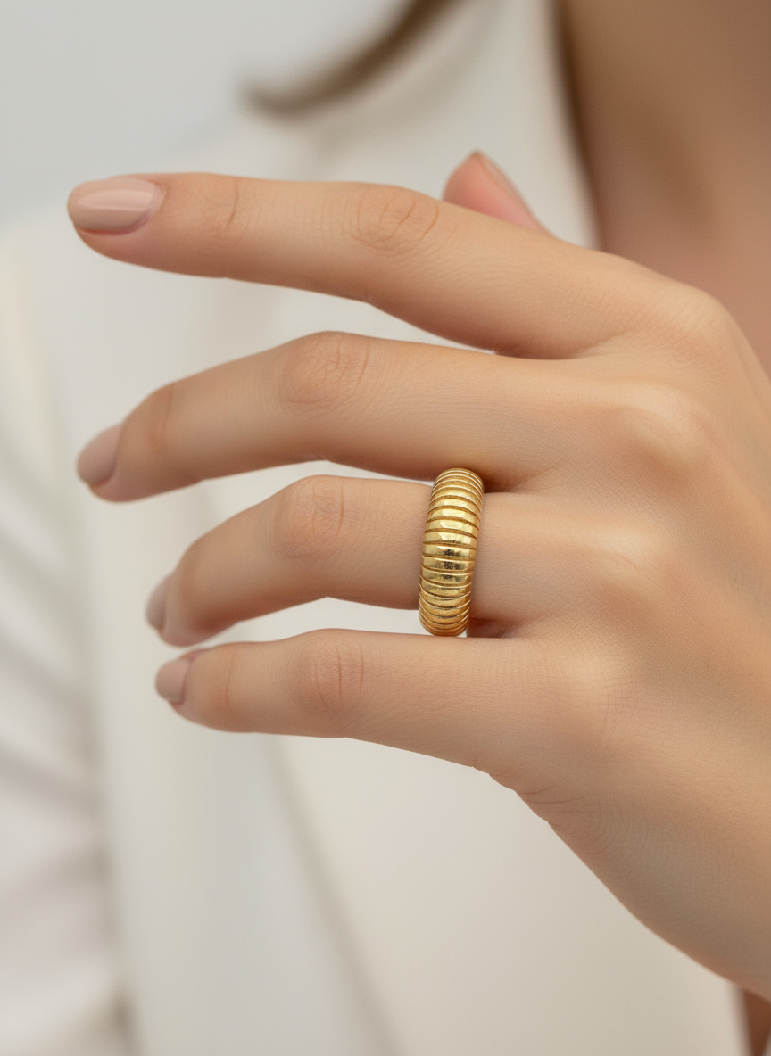Gold ring on a person's finger against a neutral background