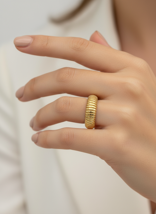 Gold ring on a person's finger against a neutral background