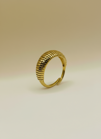 Gold ring with a ribbed design on a beige background