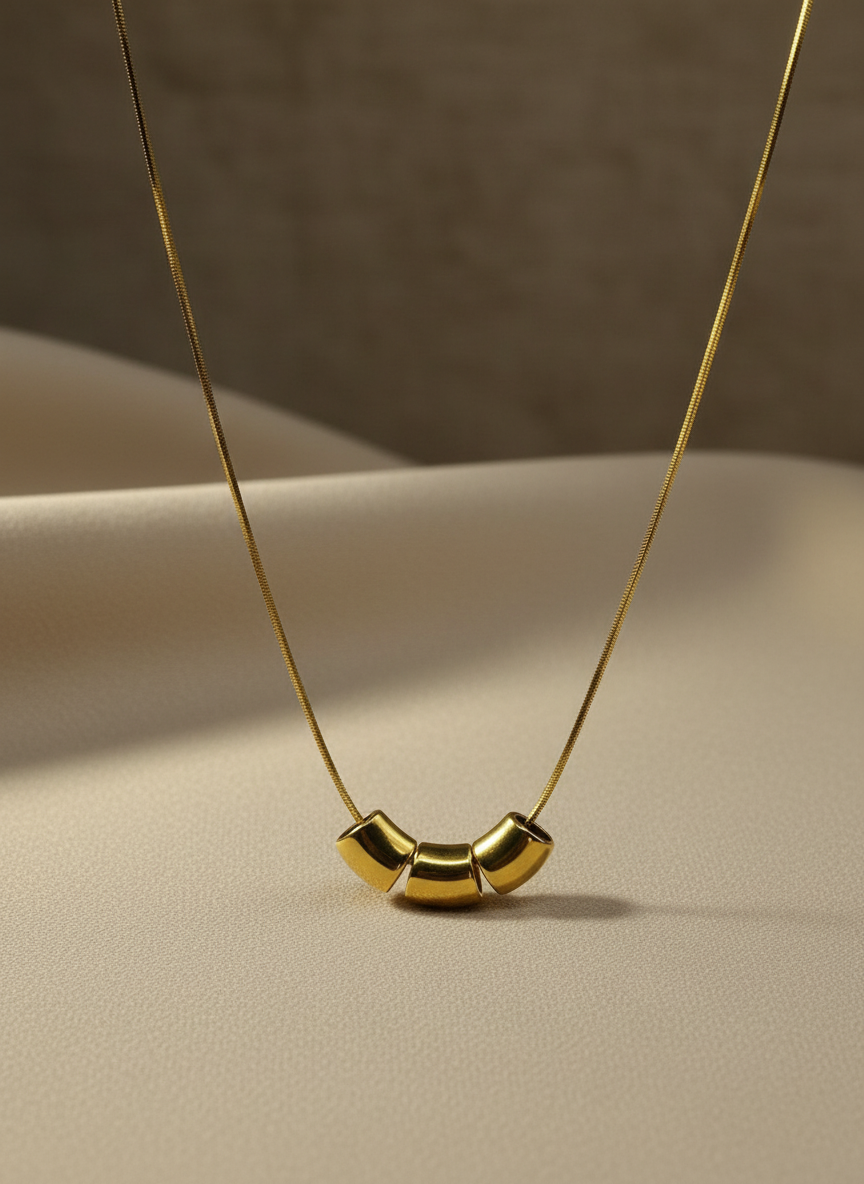Gold necklace with a unique pendant on a beige surface