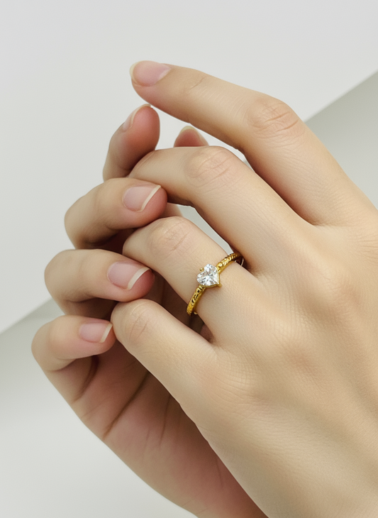 Gold ring with a diamond on a hand against a neutral background