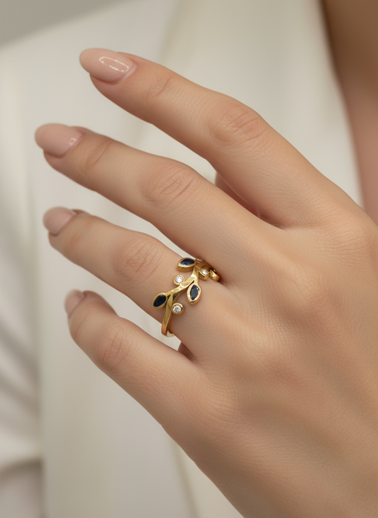 Gold ring with blue stones on a hand against a neutral background