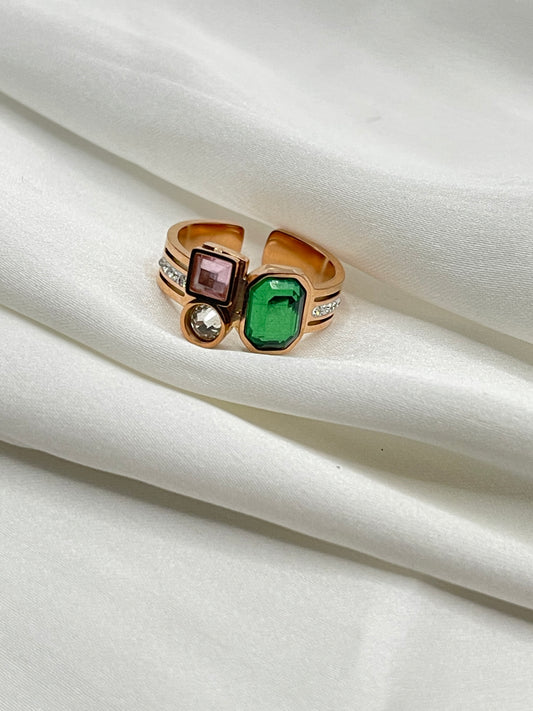 RoseGold ring with green and purple gemstones on a white fabric background