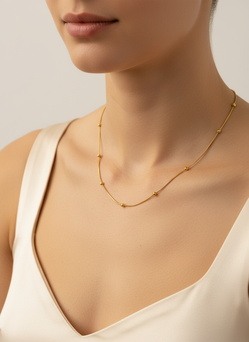 Gold necklace worn by a model against a neutral background