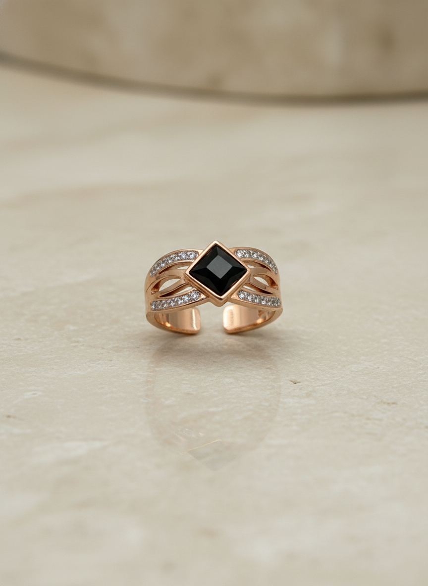 Rose Gold ring with a black gemstone on a beige surface