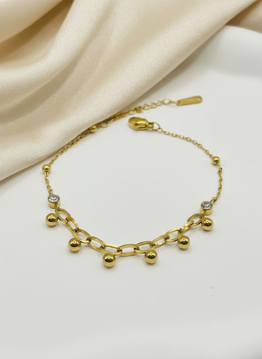 Gold bracelet with spherical beads on a white background