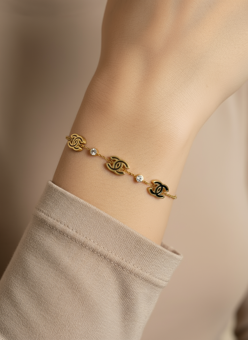 Gold chain bracelet with interlocking 'C' design on a light gray background