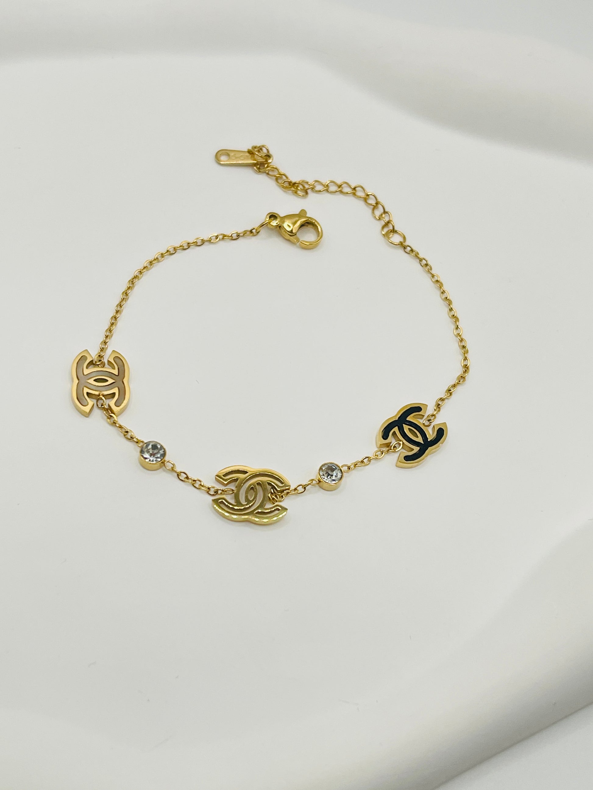 Gold bracelet with Chanel logos on a light gray background