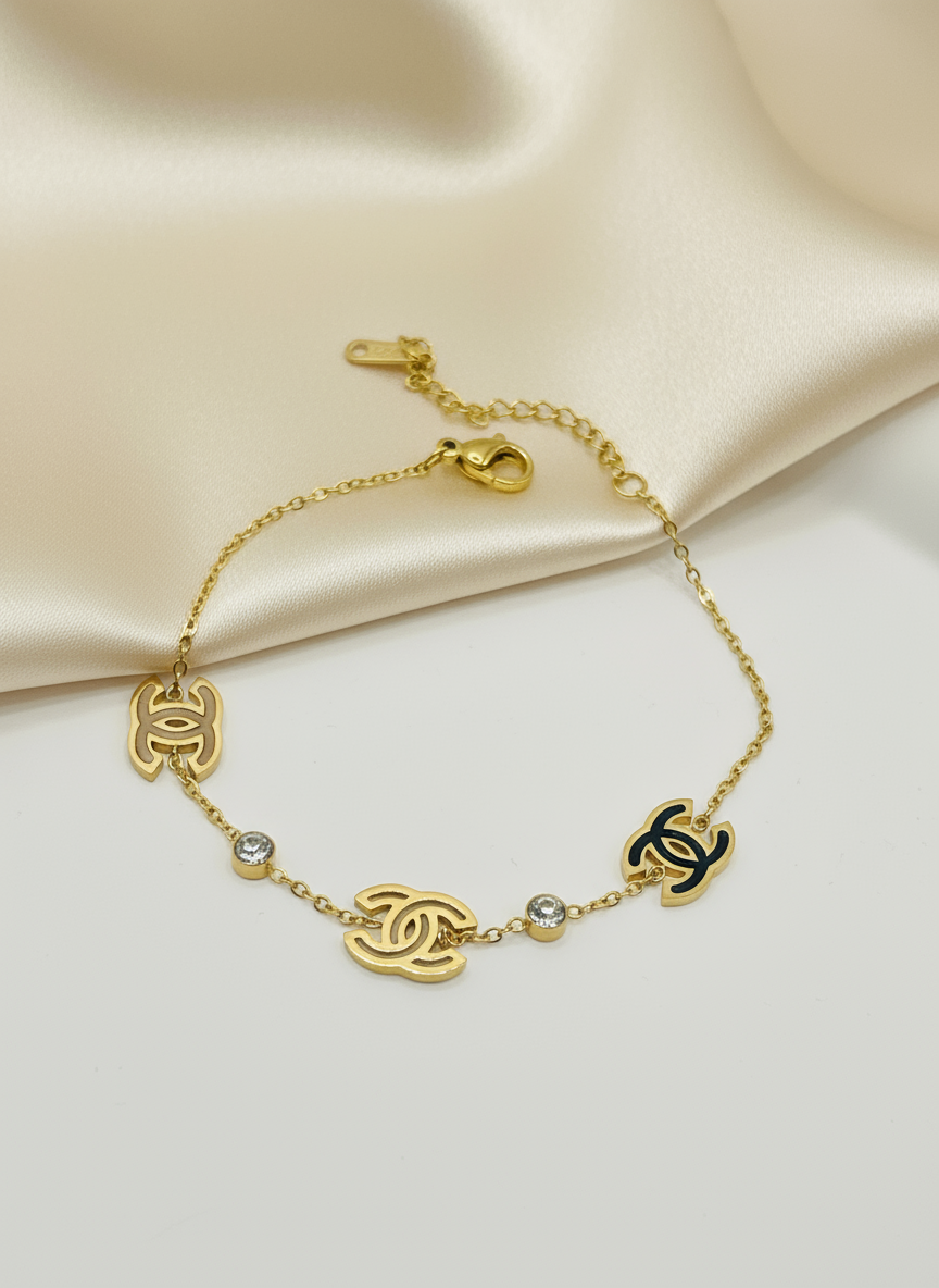 Gold bracelet with Chanel logo on a beige fabric background