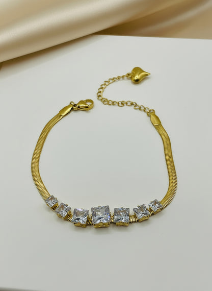 Gold bracelet with clear gemstones on a light gray background