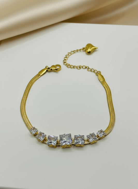 Gold bracelet with clear gemstones on a light gray background