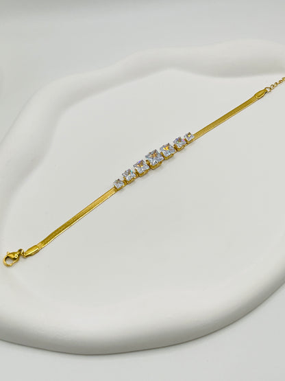 Gold bracelet with crystals on a light gray background