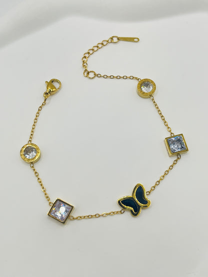 Gold bracelet with butterfly and gemstone charms on a white background