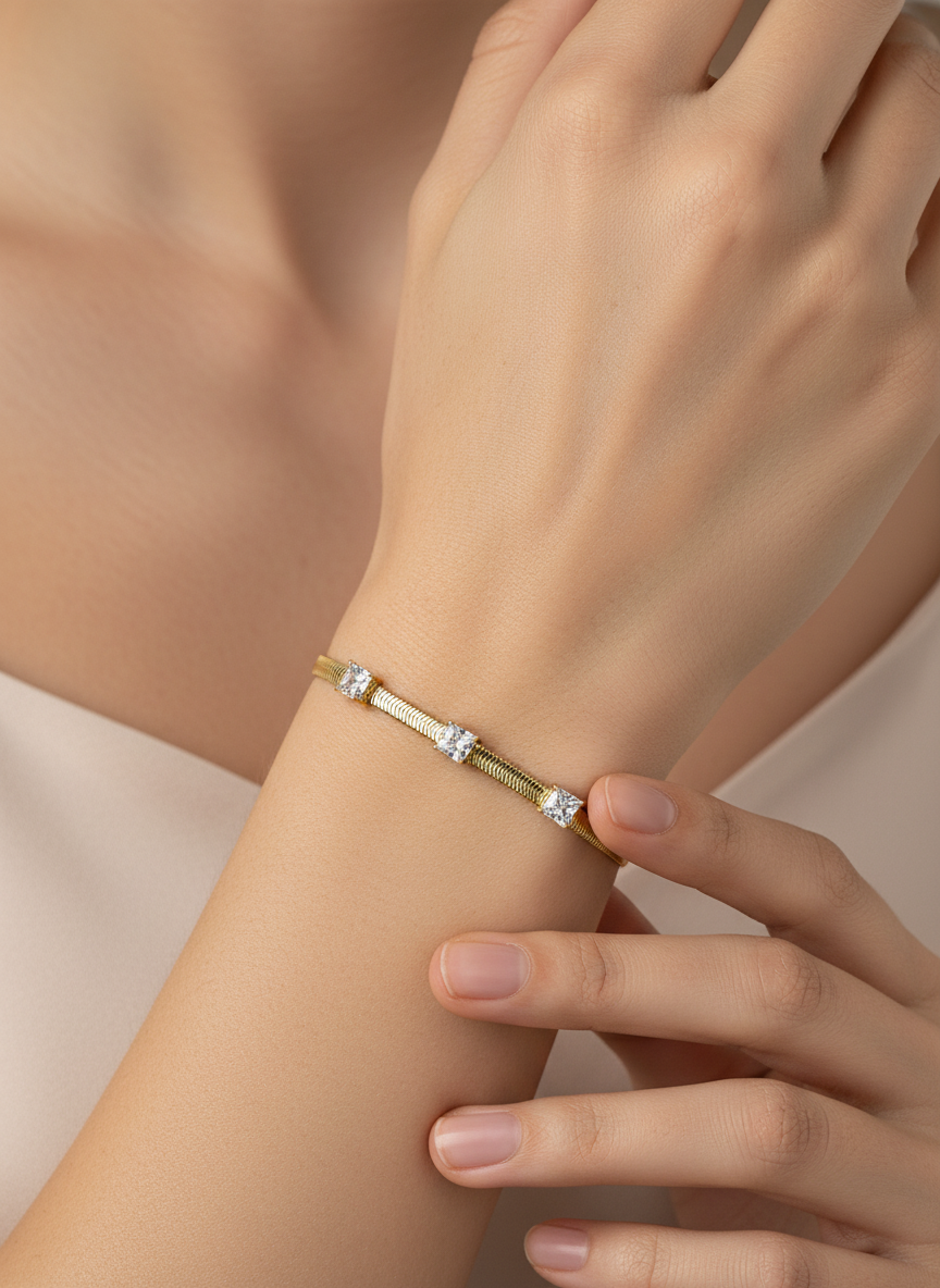 Gold bracelet with diamond-like stones on a light gray background