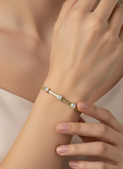 Gold bracelet with diamond-like stones on a light gray background