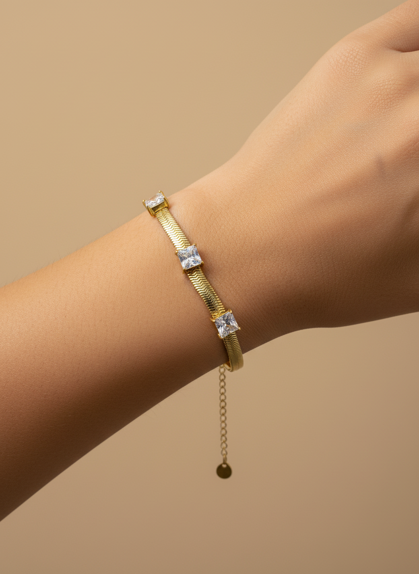 Gold bracelet with clear stones on a white background