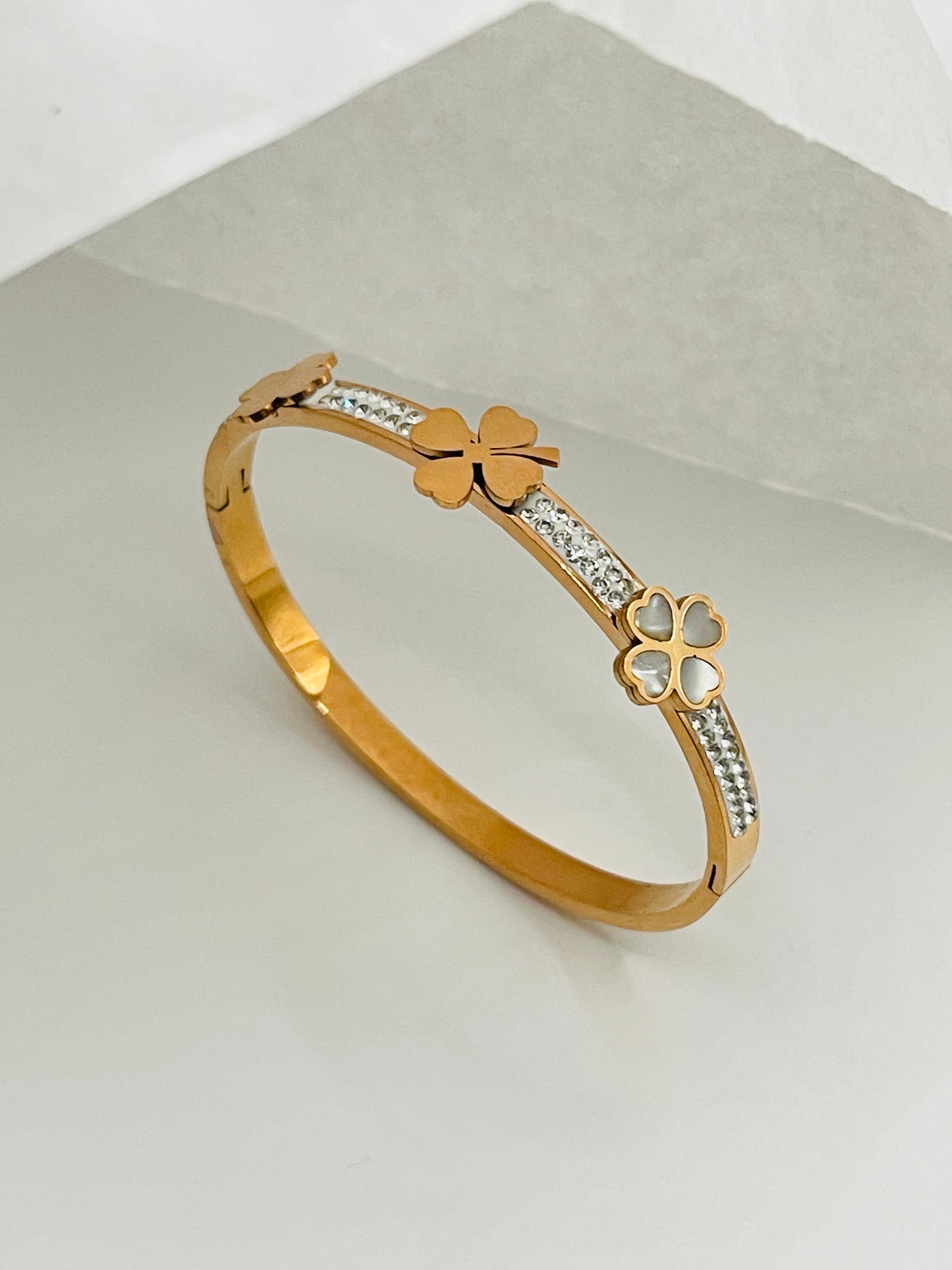 Rose Gold bracelet with clover designs on a light gray background