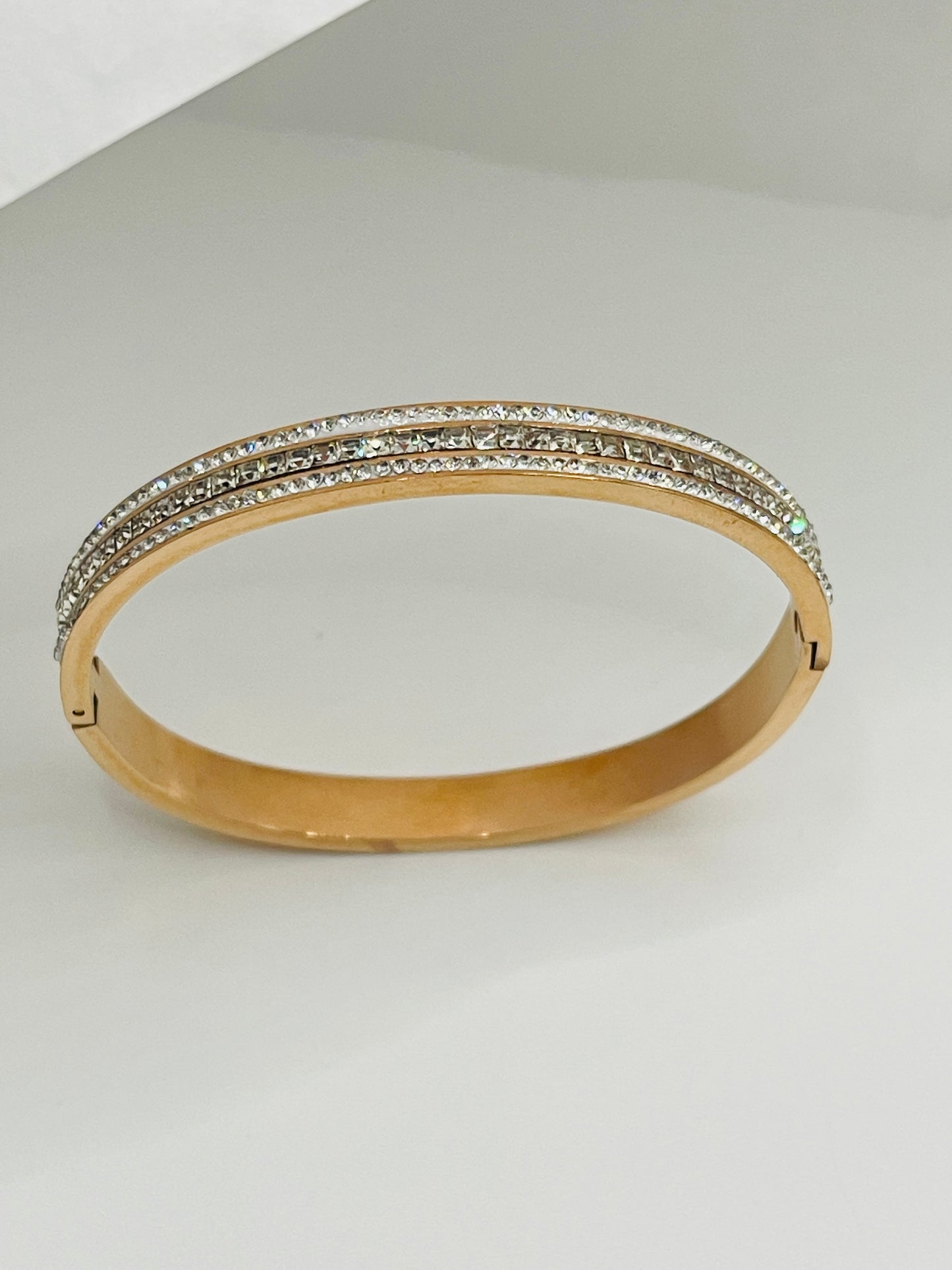Rose Gold bangle with diamond accents on a light gray background