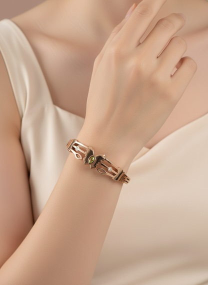 Rose gold bracelet with a green gemstone on a wrist against a neutral background