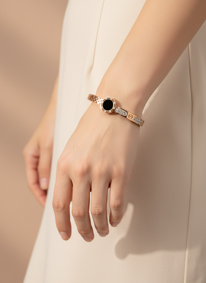Hand wearing a bracelet with a black gemstone on a neutral background