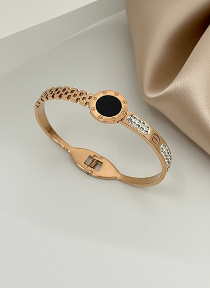 Rose gold bracelet with black gemstone and diamonds on a beige background