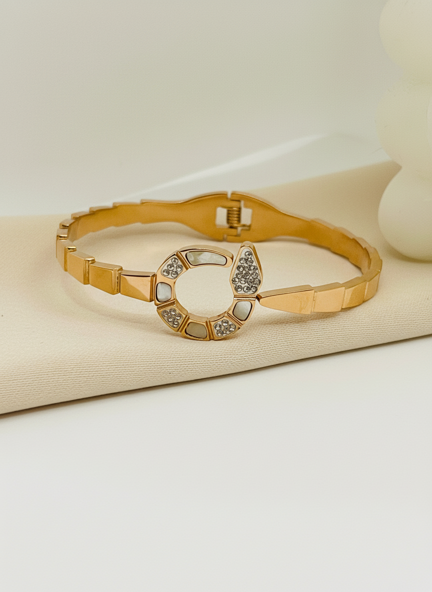 Gold bracelet with a decorative clasp on a beige surface