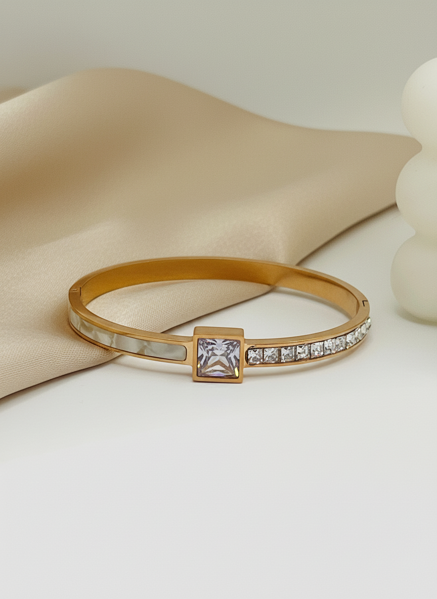 Rose Gold bracelet with a square gemstone and smaller stones on a beige fabric background