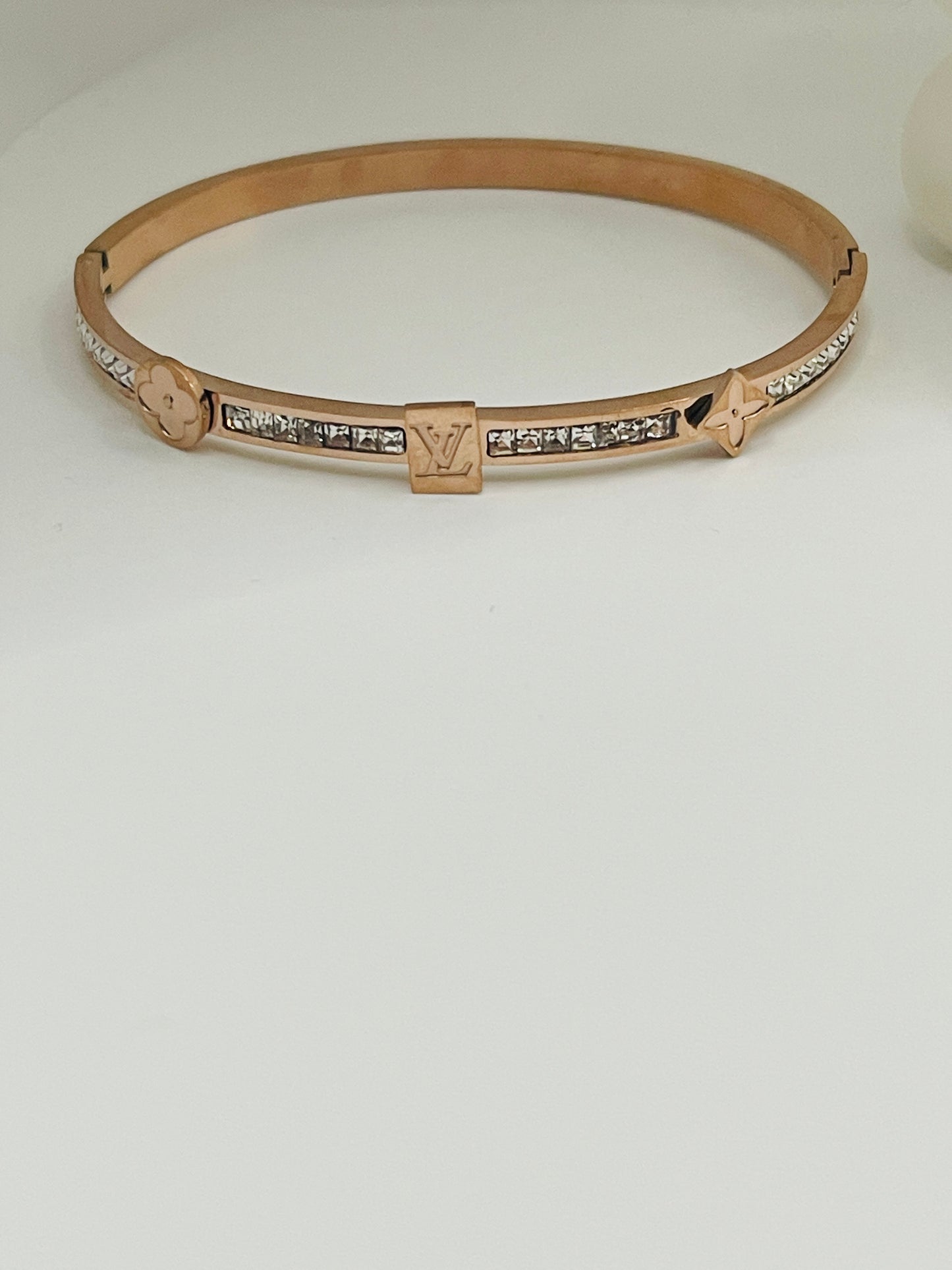 Rose gold bracelet with diamond accents on a light gray background