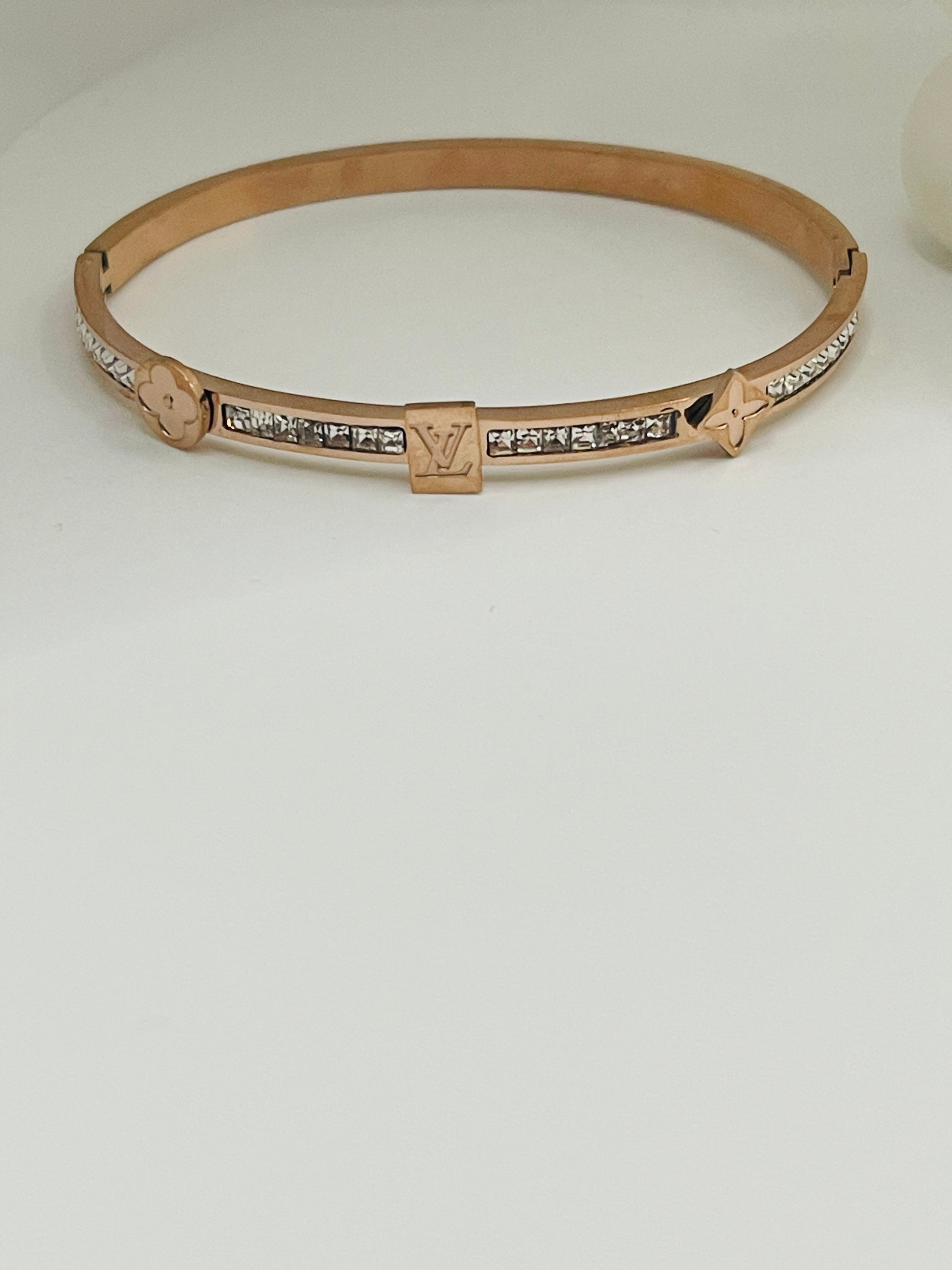 Rose gold bracelet with diamond accents on a light gray background