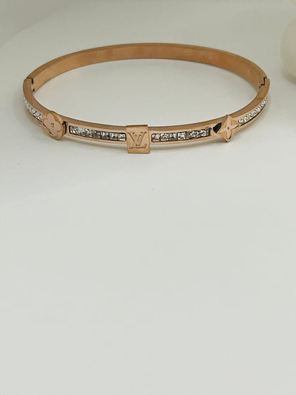 Rose gold bracelet with diamond accents on a light gray background