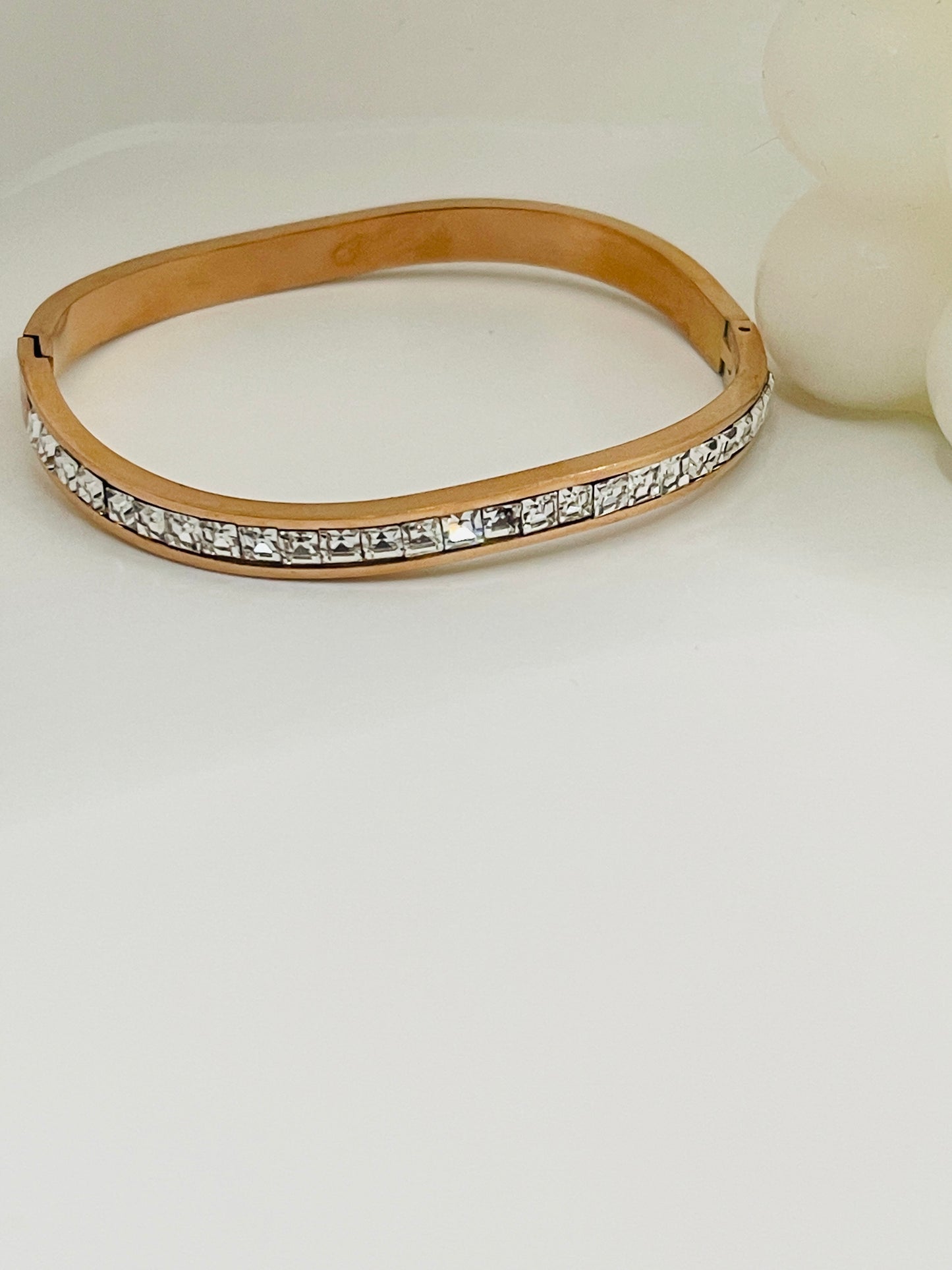Gold bangle with clear stones on a white background