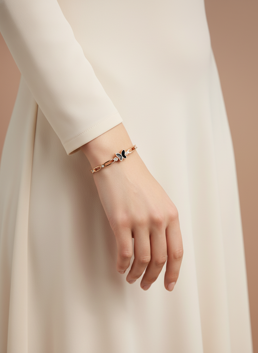 Hand wearing a delicate bracelet with a butterfly charm against a neutral background