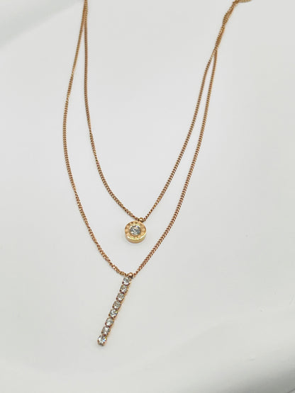 double layer gold necklaces with diamond pendants on a light gray background