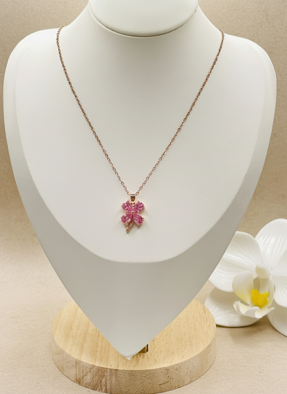 Necklace with a pink pendant on a mannequin bust with a white flower in the background