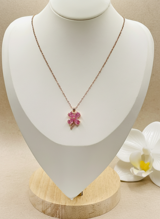 Necklace with a pink pendant on a mannequin bust with a white flower in the background