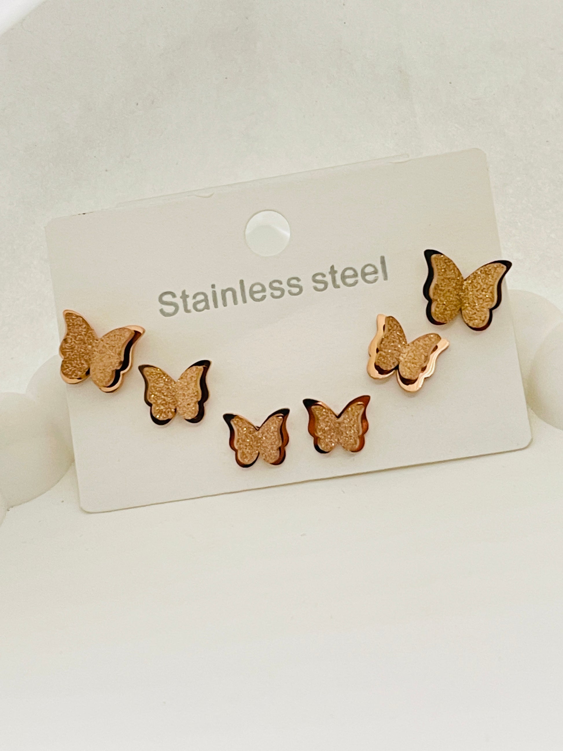 Butterfly-shaped earrings on a stainless steel card against a white background