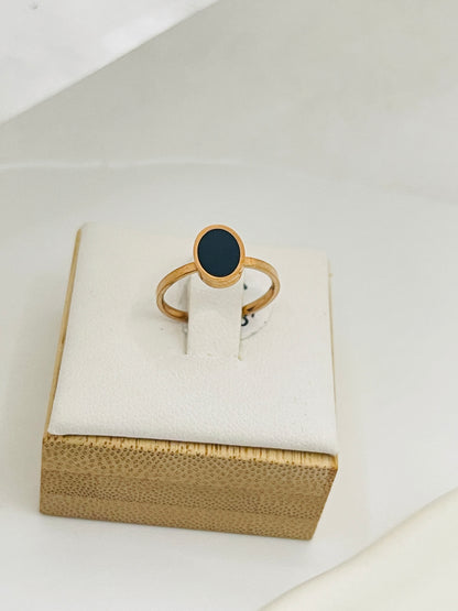 Rose Gold ring with a black stone on a white cushion inside a gold box.