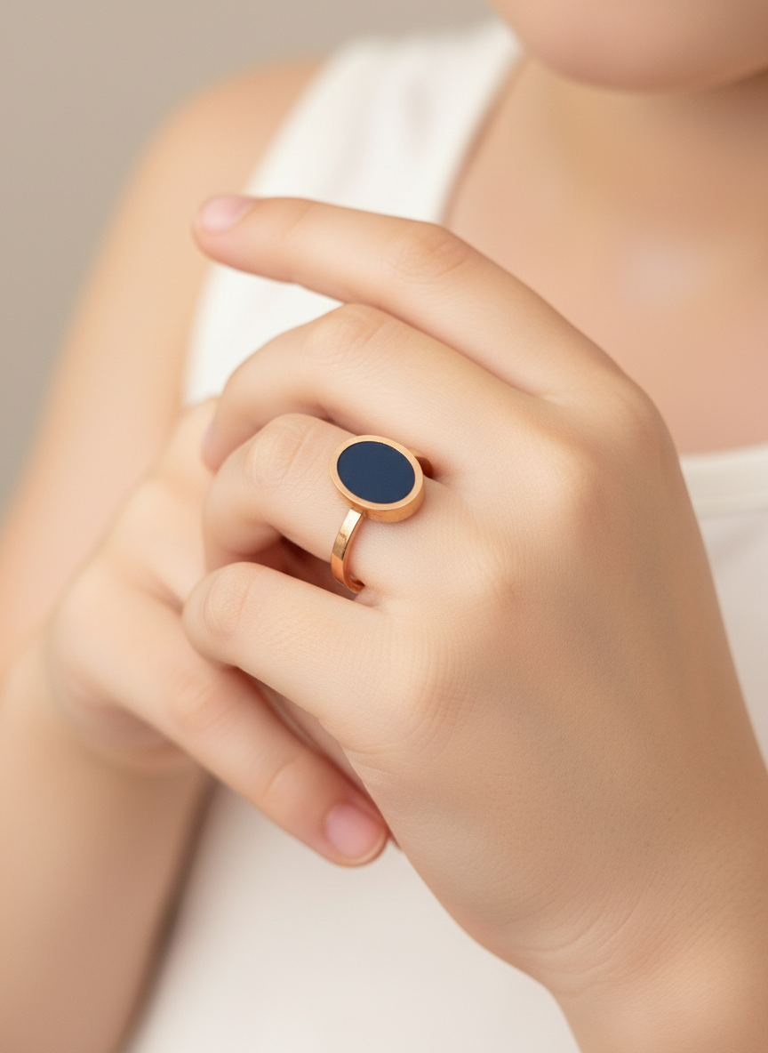 Hand wearing a ring with a black enamel  on a neutral background