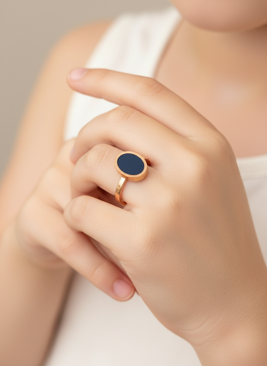 Hand wearing a ring with a black enamel  on a neutral background