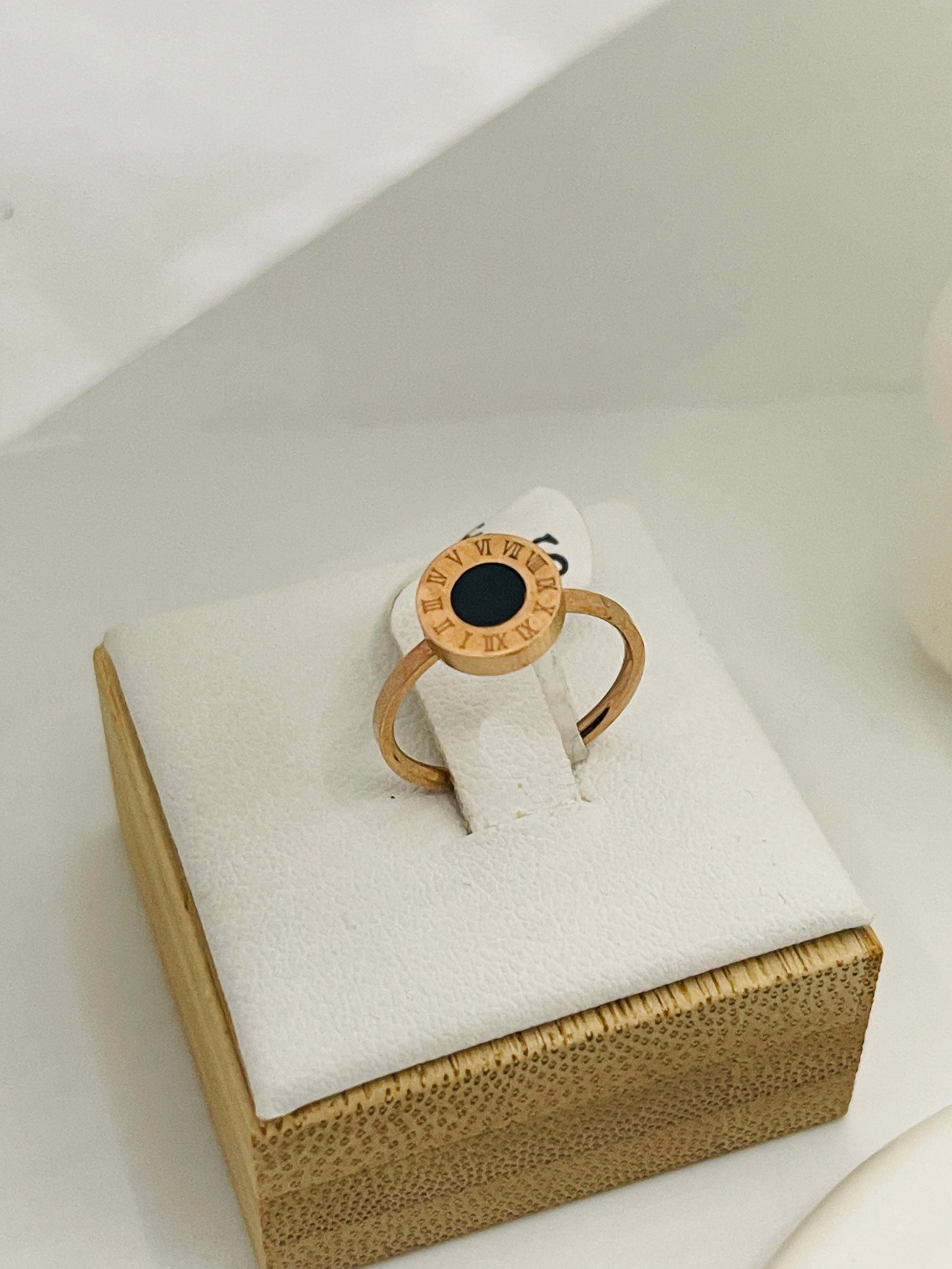 Rose Gold ring with a black gemstone on a white cushion inside a brown box.