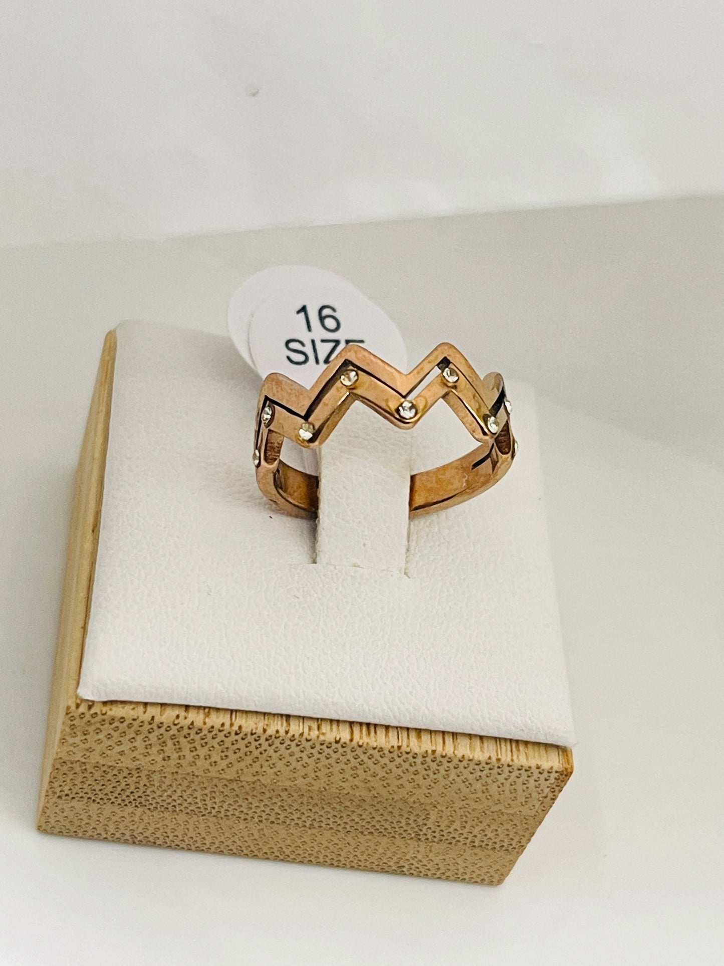 Gold ring on a white cushion with a size label in a wooden box