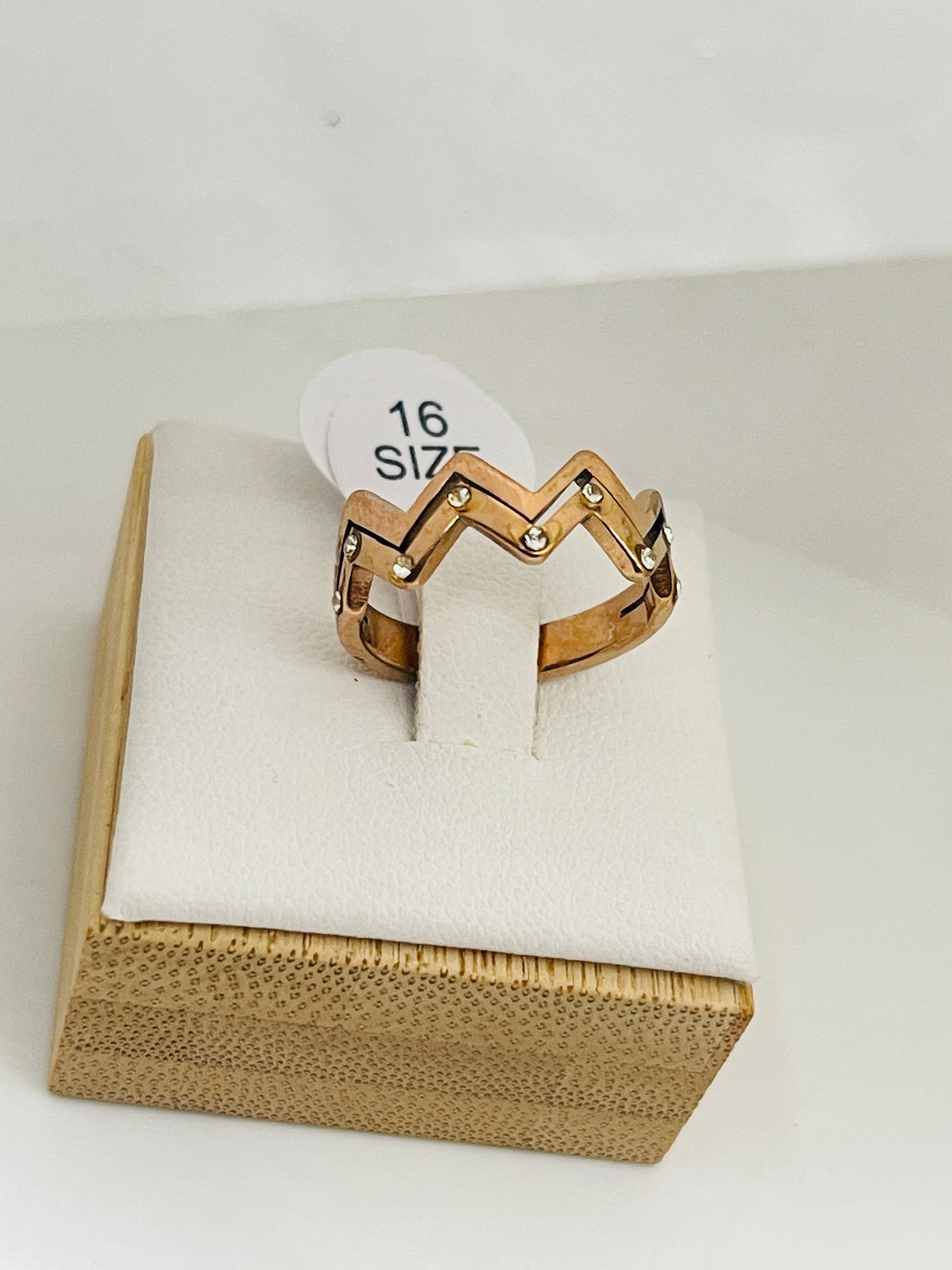 Gold ring on a white cushion with a size label in a wooden box