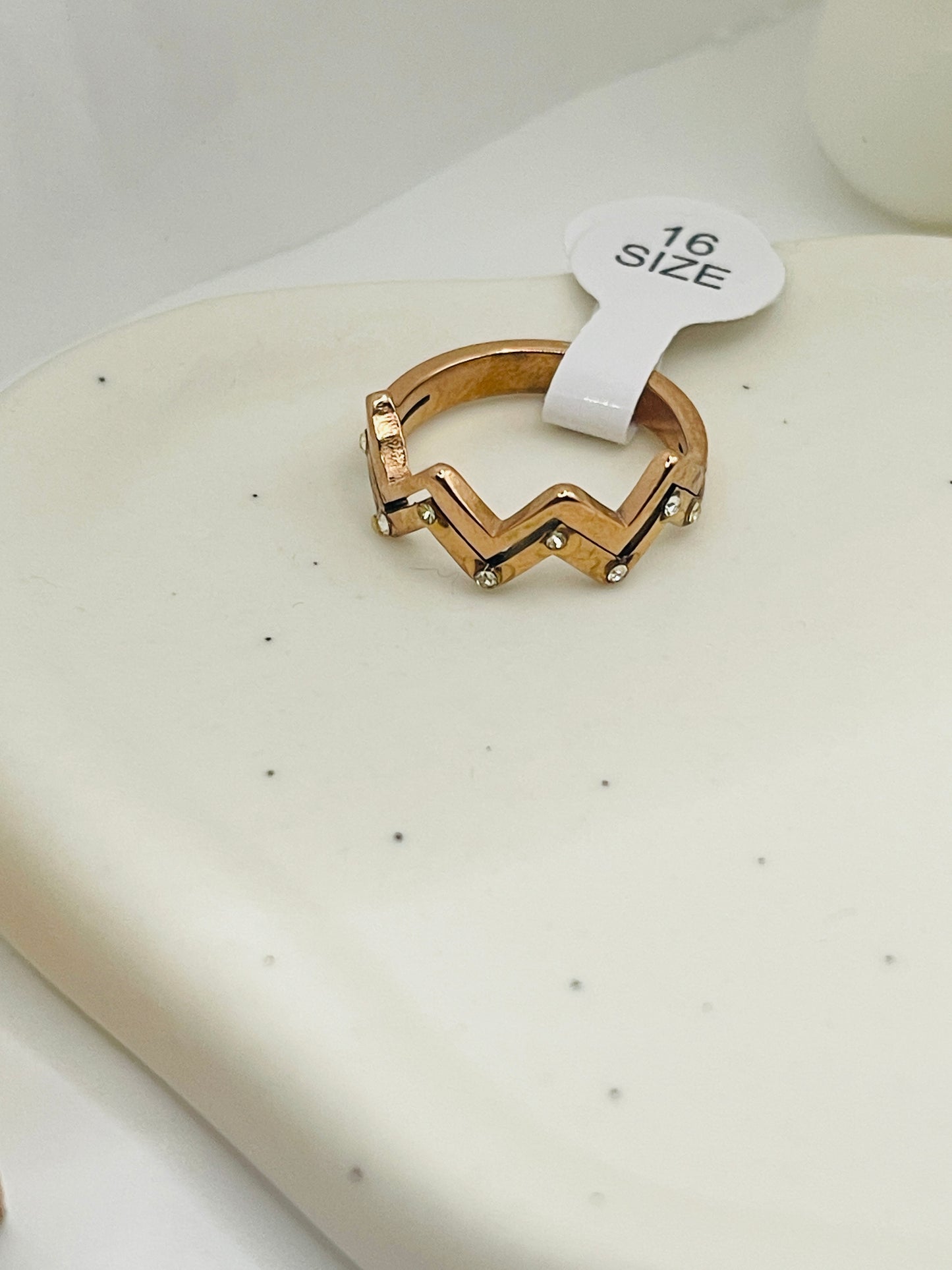 Rose Gold ring with a size tag on a white surface